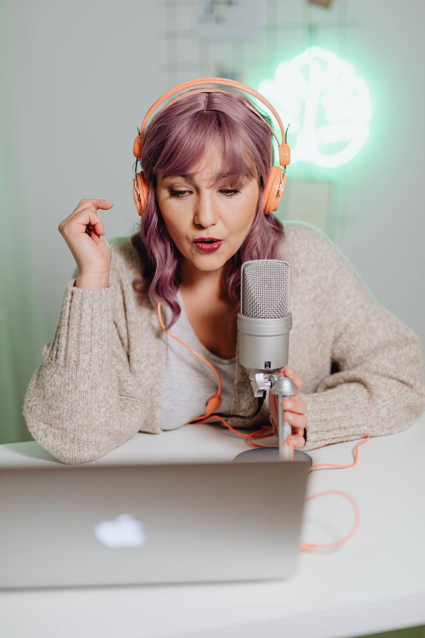 a woman talking on a microphone while wearing a headphone