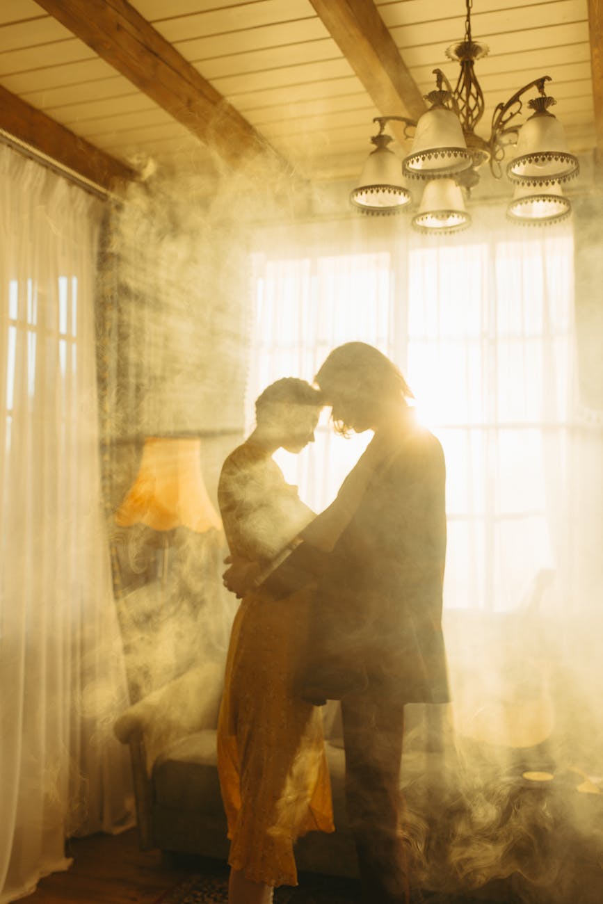 couple backlit by the sun flare through the window with curtain